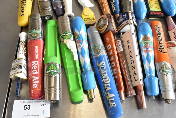 44 assorted beer tap handles, brands include Blue Moon, Oktoberfest, Surly. Variety of designs and colors, good condition.