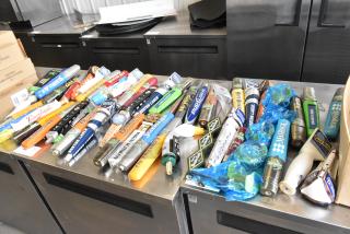 55 various beer tap handles, including brands like Samuel Adams, in good condition, displayed on a table.