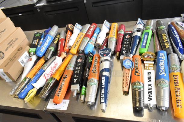 55 various beer tap handles, including Samuel Adams, displayed on a table. Brands and styles vary; ideal for collectors.