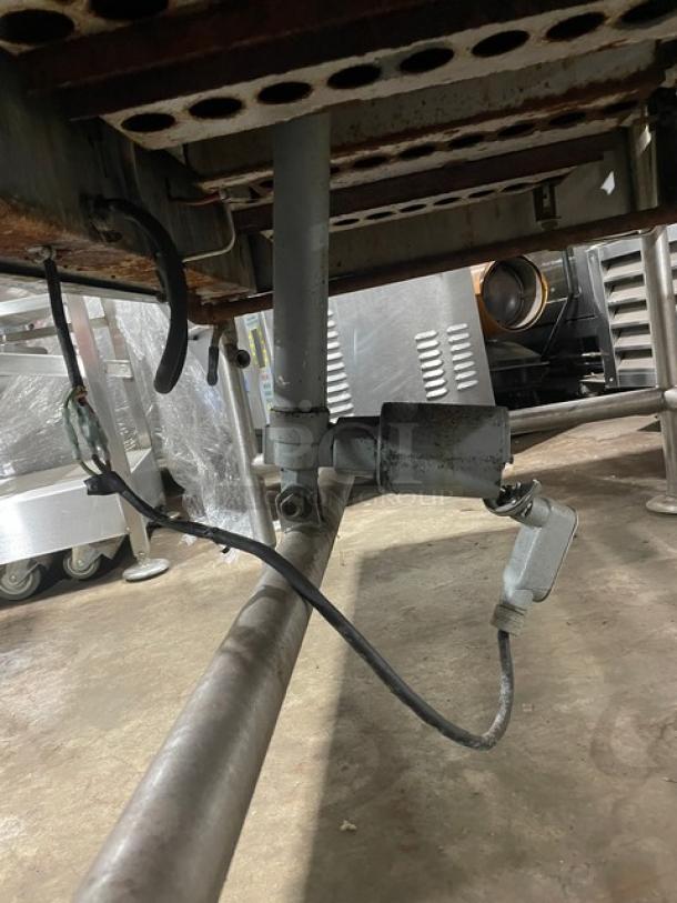 Vulcan stainless steel tilted braising pan, natural gas-powered, on legs. Visible pipes and connections, industrial setting.