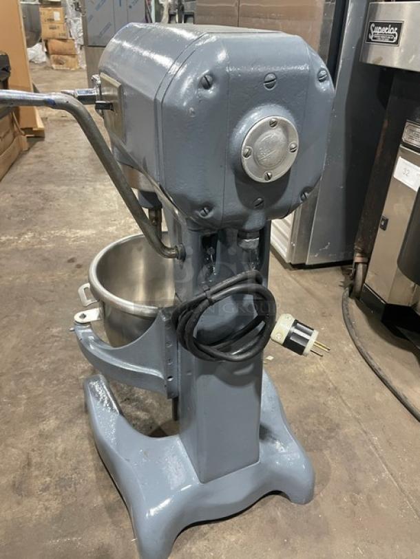 Hobart commercial electric planetary mixer with mixing bowl, heavy-duty, on legs, equipped with power cord, in industrial setting.