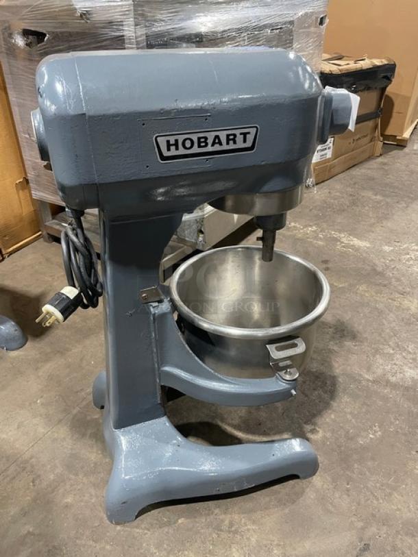 Hobart commercial electric planetary mixer in working condition, includes mixing bowl; features sturdy legs, visible power cord.