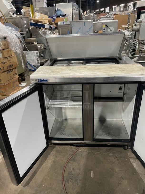 True TSSU-3608 stainless steel 2-door refrigerated prep table, cutting board, pans, poly-coated rack, on casters, open doors.
