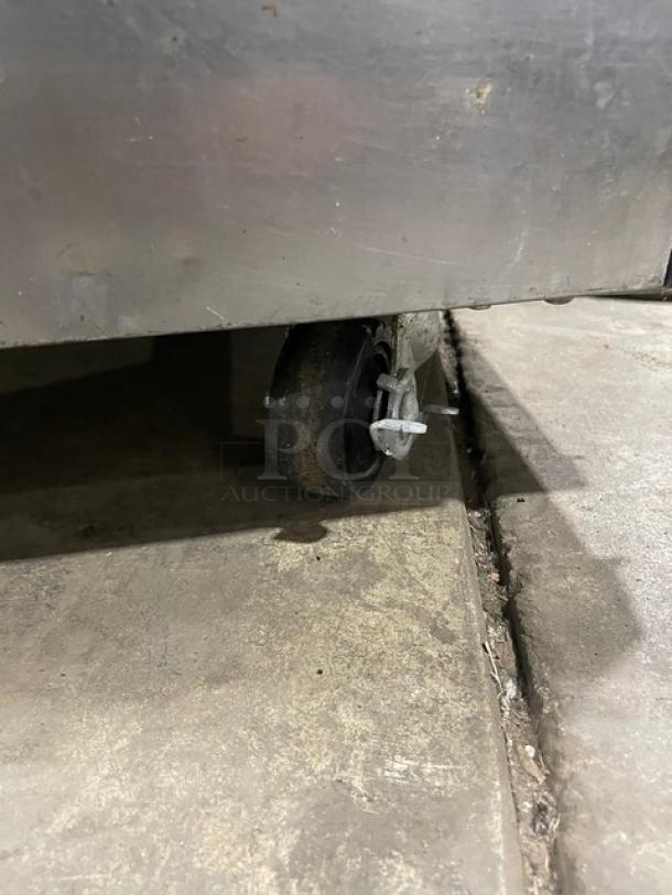 True TSSU3608 refrigerated bain marie prep table caster close-up, showing stainless steel body and wheel locking mechanism.