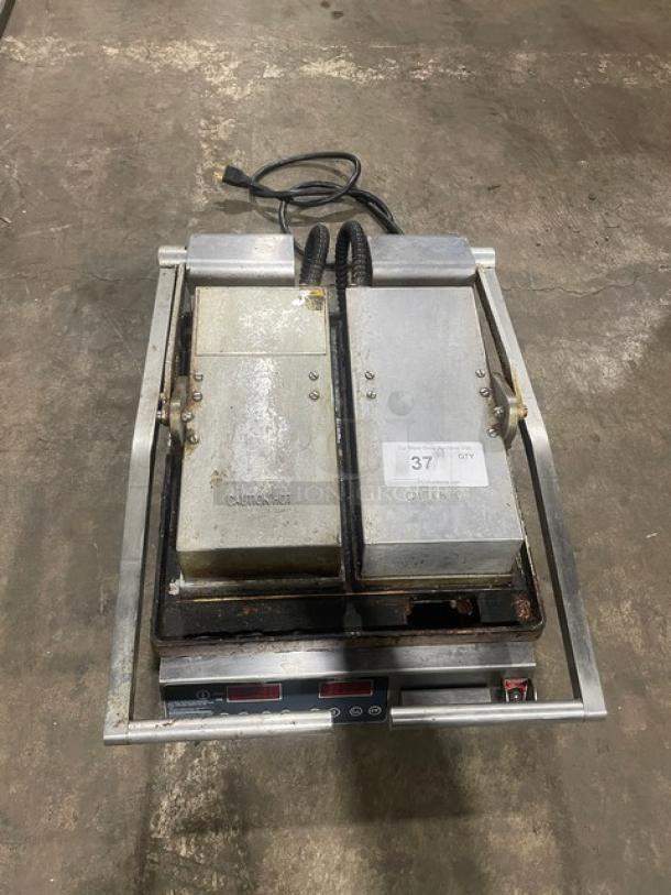 Commercial stainless steel electric countertop dual panini press grill with two heated plates. Used condition, on legs.