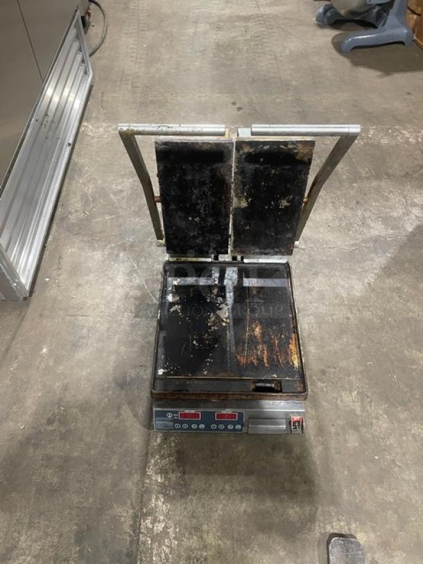 Commercial stainless steel dual panini press grill, electric powered, with countertop design. Visible wear and rust.