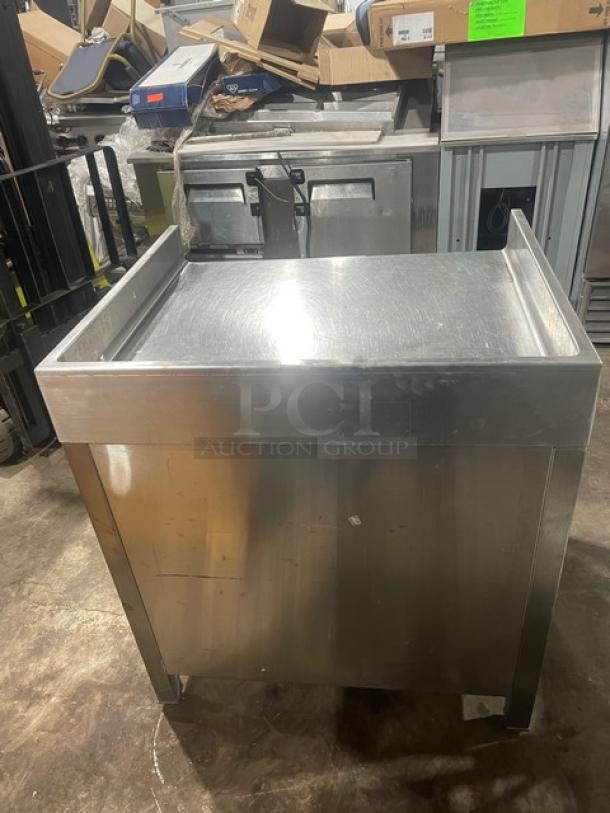 Commercial stainless steel worktop table with enclosed cabinet base, up-turned back and side splash, on sturdy legs.