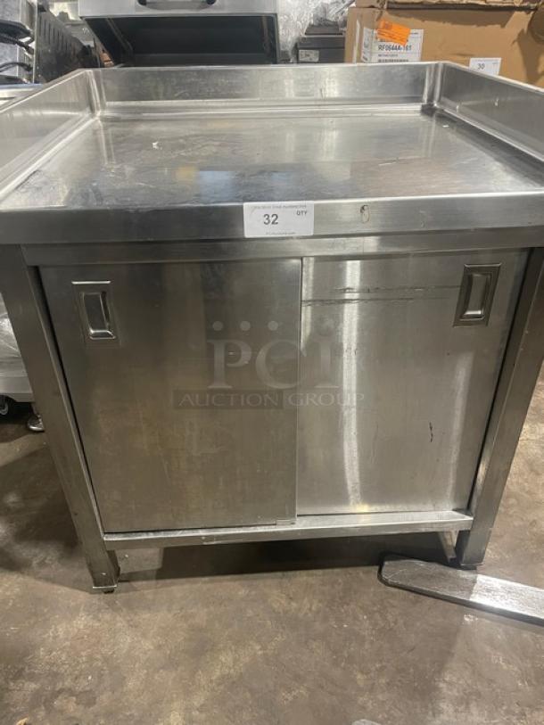 Commercial stainless steel worktop table with enclosed cabinet base, up-turned back and side splash, on legs, labeled "32".