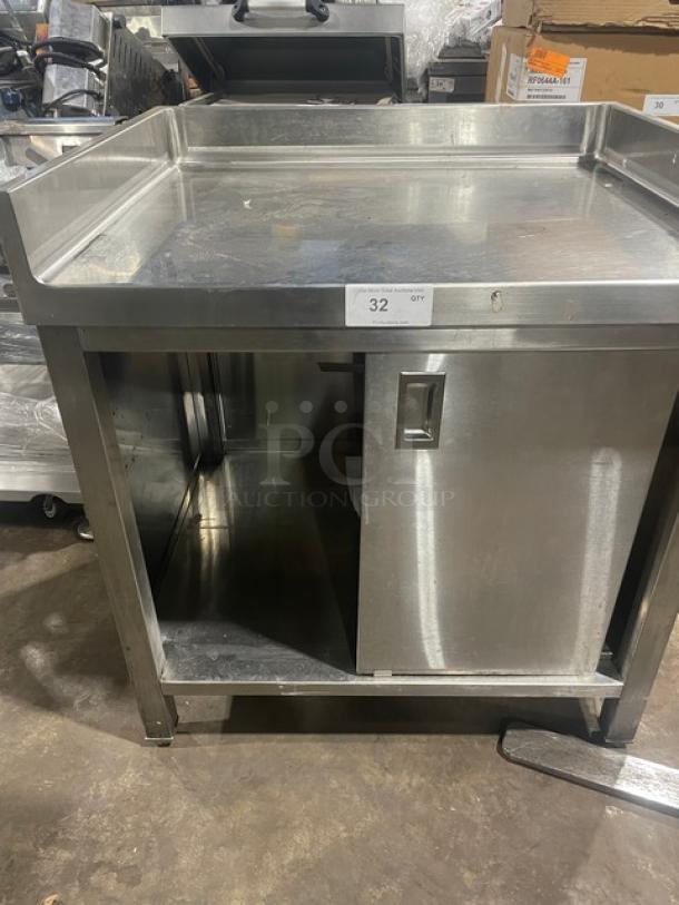 Commercial stainless steel worktop table with enclosed cabinet base, up-turned back and side splash, on legs.