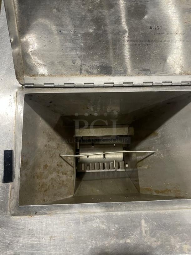 Commercial stainless steel ice crushing machine, wooden style design, on legs. Interior view showing crushing mechanism; used condition.