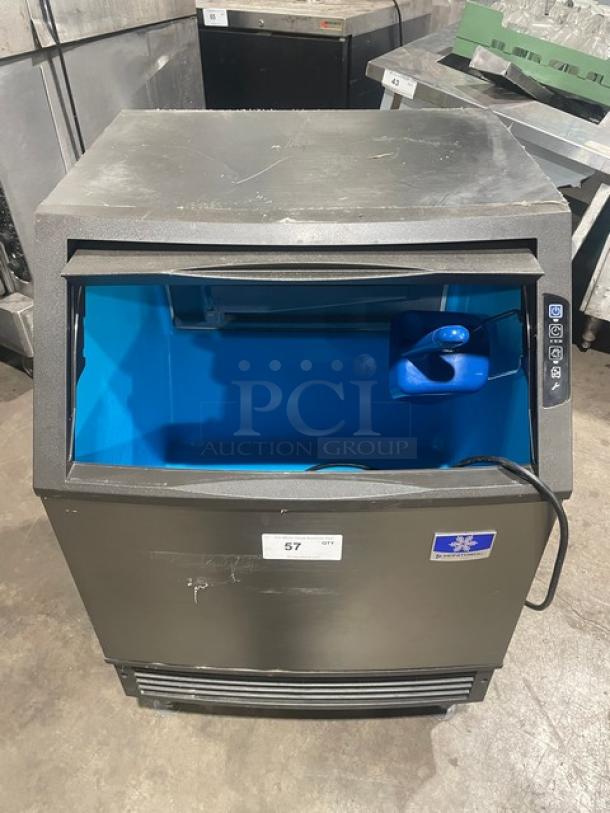 Manitowoc stainless steel undercounter ice maker, electric-powered, SN: 310620659, 115V, on legs, open bin visible.