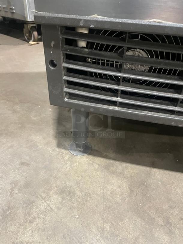 Manitowoc stainless steel undercounter ice maker on legs, electric 115V, commercial grade, with visible fan and housing detail.