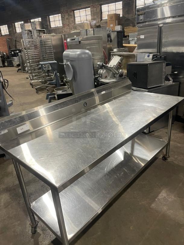 Commercial stainless steel prep table with single undershelf, upturned back splash, and casters; excellent condition.