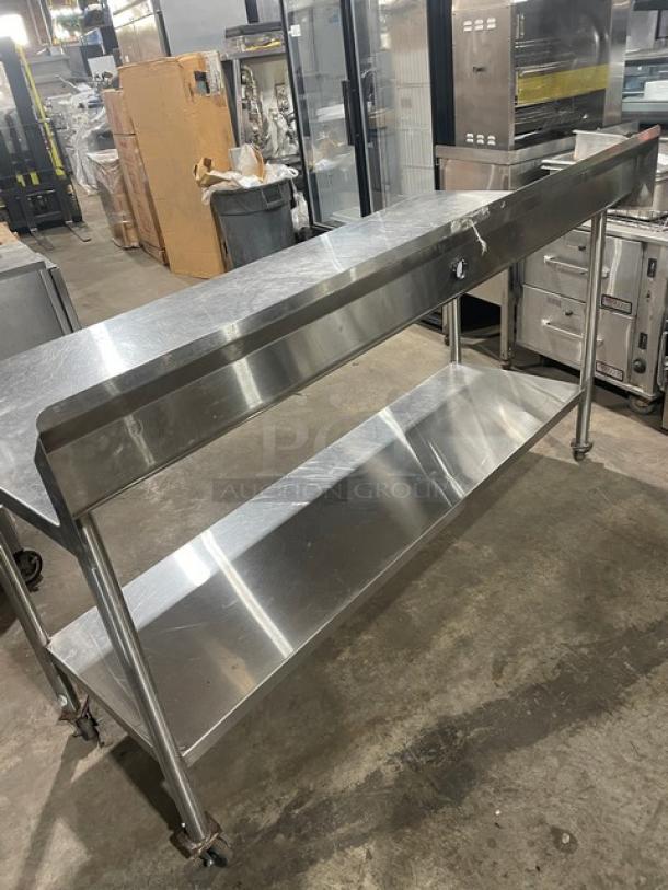Commercial stainless steel worktop prep table with single undershelf, upturned backsplash, and casters. Used condition.