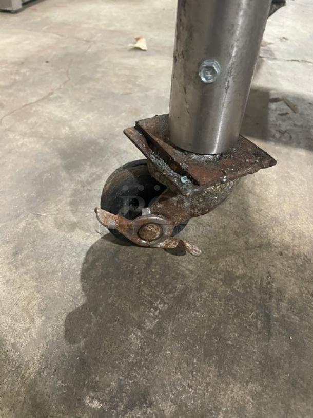 Rusty caster wheel on a commercial stainless steel worktop prep table.