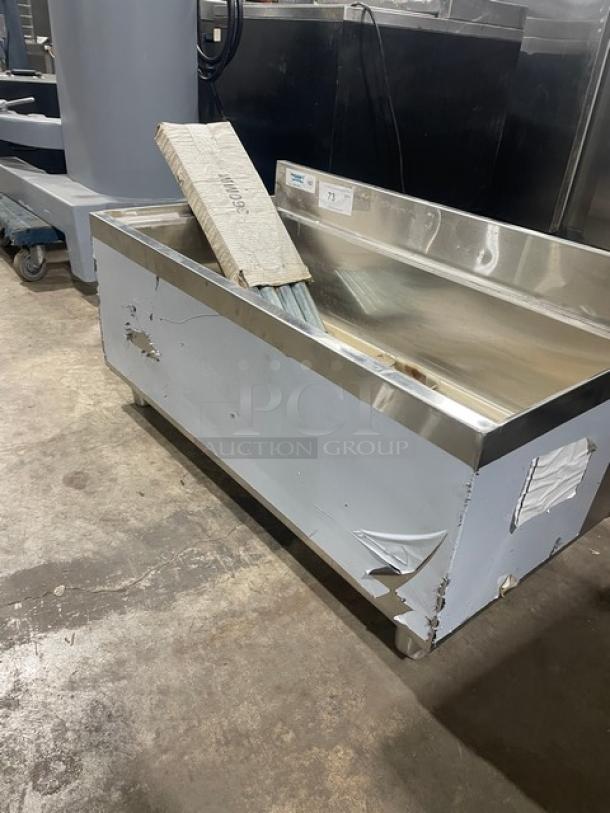 Regency stainless steel single well ice bin with upturned backsplash, scratches, dents, and attached legs. New condition with defects.