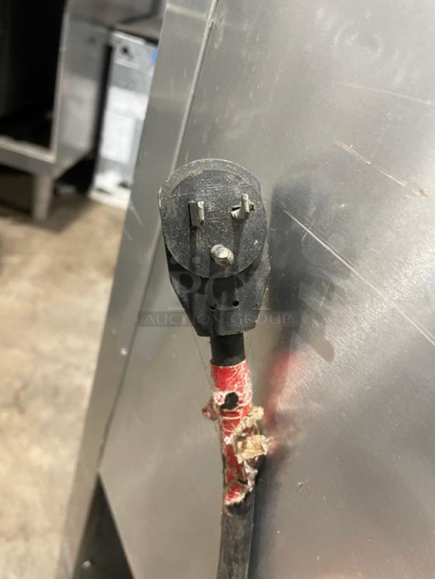 Close-up of a power cord and plug for a True T-49F commercial freezer, showing signs of wear.