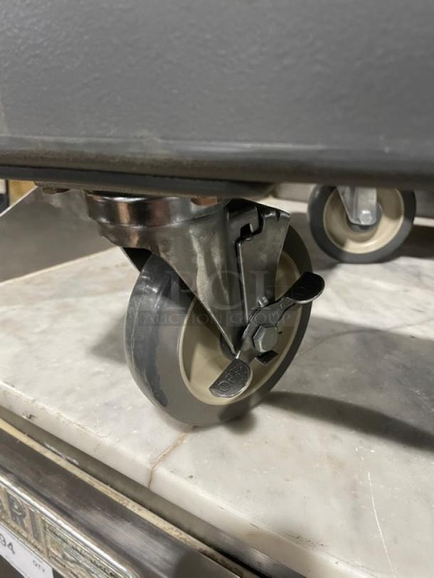 Cambro commercial gray food pan carrying dolly with sturdy casters. Features durable construction, ideal for kitchen use.