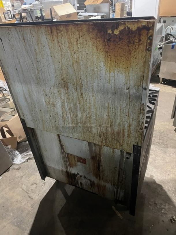 Vulcan stainless steel commercial 6-burner range/oven combo with overhead salamander shelf, raised backsplash, on legs. Rust visible on the back.