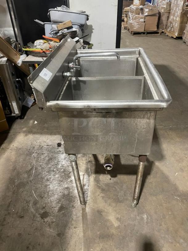 Stainless steel 2-compartment dishwashing/prep sink with faucet and legs, in used condition.