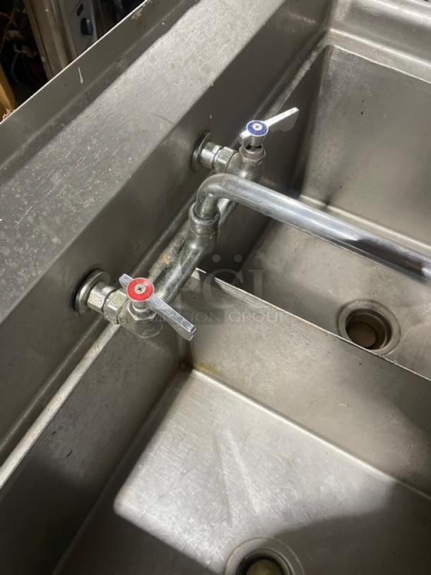 Stainless steel 2-compartment sink with faucet and legs, ideal for dishwashing or prep, features dual drain openings.