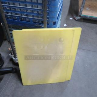 Yellow 18x24 cutting board with slight wear, standing upright. No visible markings or labels.