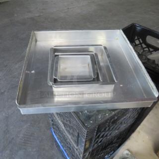 Assorted size baking pans stacked; three square pans made of metal in varying dimensions. Used condition.