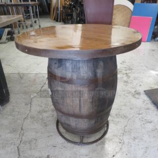 Bar-height table made from a reclaimed whiskey barrel, 41x42 inches. Features polished wood top, metal bands. Rustic charm.