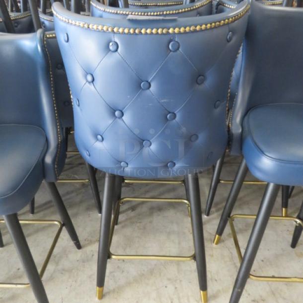 Vintage-look blue cushioned bar stool with a swivel seat, tufted back, nail head trim, and gold footrest; sturdy condition.