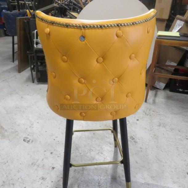 Yellow cushioned bar stool with swivel seat, tufted back, nail head trim, and gold footrest. Vintage look. Counter height.