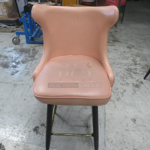 Vintage-style pink bar stool with cushioned swivel seat, tufted back, nailhead trim, and gold footrest.