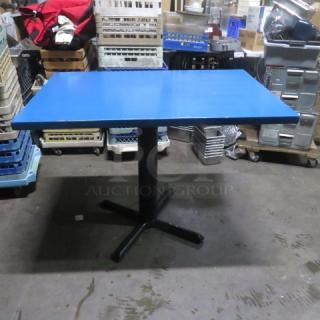 Blue solid wooden table on bar height pedestal base, 46x30x35.5 inches, in good condition.