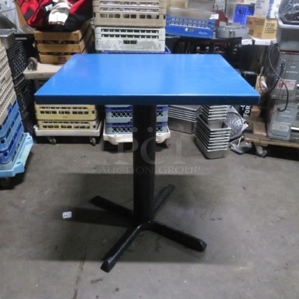 Blue solid wooden table on black bar height pedestal base, 24x30x35.5 inches. Good condition.
