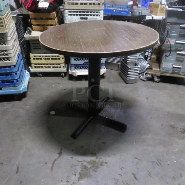 Round wooden table top on bar height pedestal base, 36x42 inches, used condition. Sturdy black metal base, natural finish.