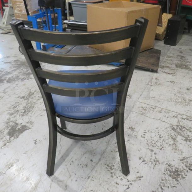 Metal chair with a blue cushioned seat, black frame, ladder-back design, in used condition. Ideal for indoor use.