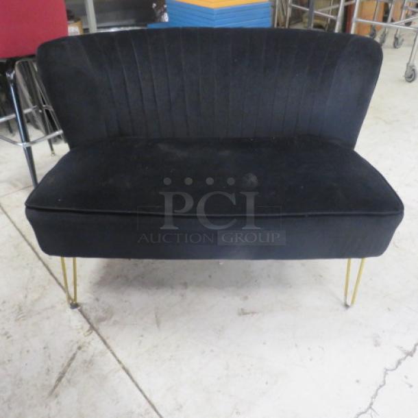 Black cushioned sofa, dimensions 45x32x31 inches, features vertical stitching on backrest, gold metal legs. Good condition.
