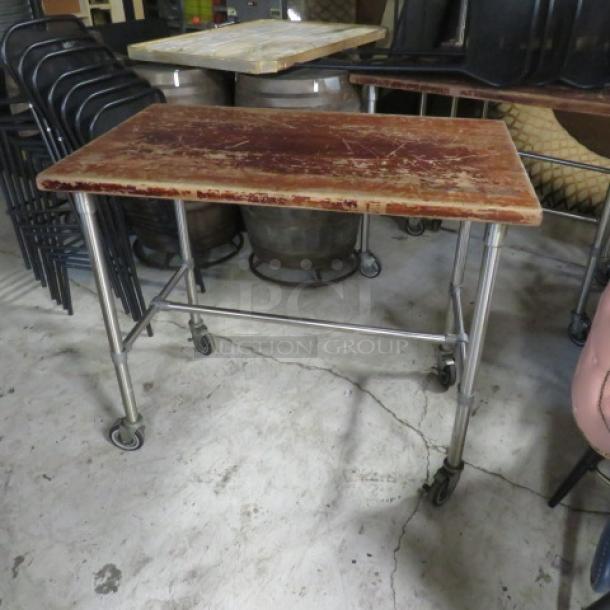 One butcher block wooden table on a stainless steel base with casters, dimensions 48x30x41 inches, visible wear.