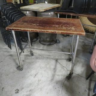 One butcher block wooden table on stainless steel base with casters, 48x30x41 inches, visible wear on top surface.