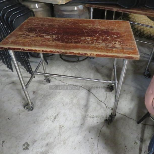 Butcher block wooden table with a stainless steel base on casters, 48x30x41 inches, features a worn surface.