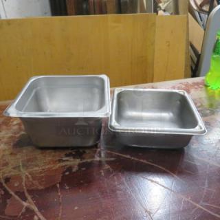 Assorted size metal hotel pans, one deep and one shallow, on a wooden surface; used condition.