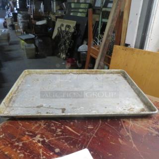 Full-size sheet pan, used, metal surface with visible wear and discoloration, model 5XBID, resting on a wooden table.