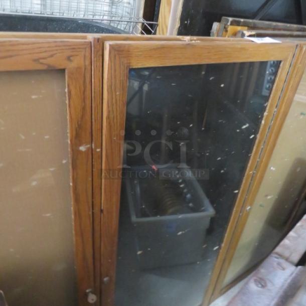 Three-door wooden framed bulletin board enclosure, 72x48 inches, with key. Moderate wear, suitable for public notices.