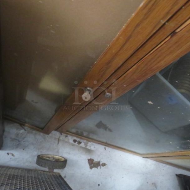 Wooden framed 3-door bulletin board enclosure with lock and key, 72x48 inches, showing wear on glass and wood.