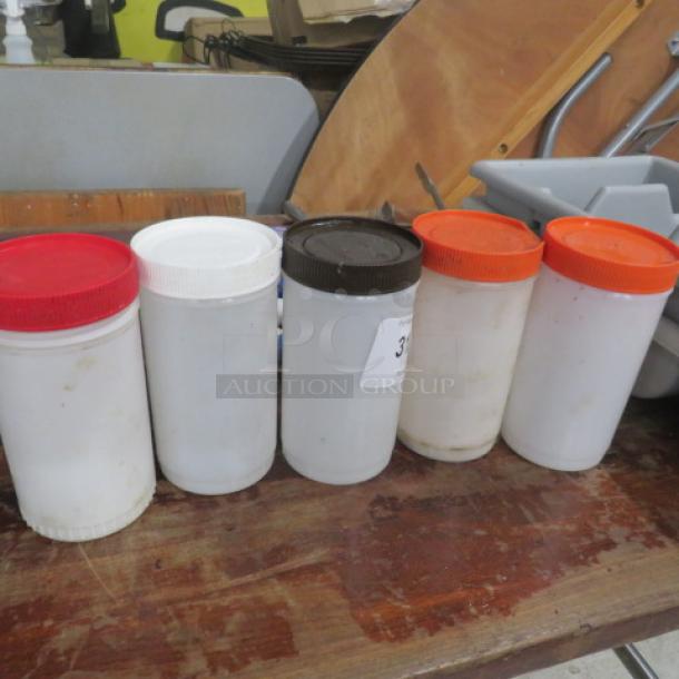 Set of five Store and Pour containers with colored lids; used condition; ideal for kitchen or bar storage and pouring.