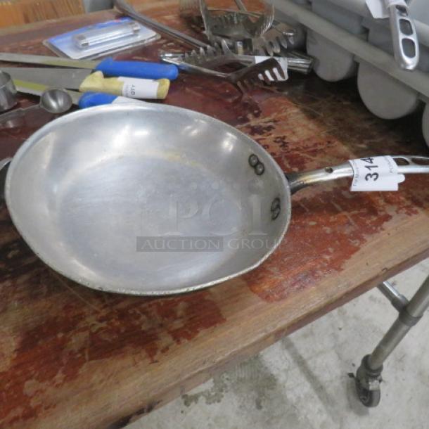 10-inch metal sauté pan on wooden surface, used condition, with a tagged handle labeled "314".