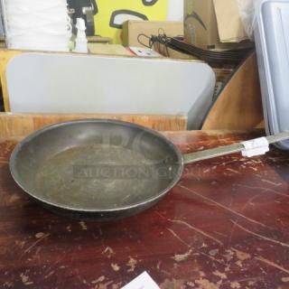 14.5-inch fry pan with long handle, metal construction, moderate wear, sitting on a wooden surface.