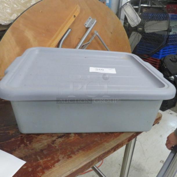 Gray bussing tub with lid on a wooden table. Lid features a white label with the number 349. Used condition.