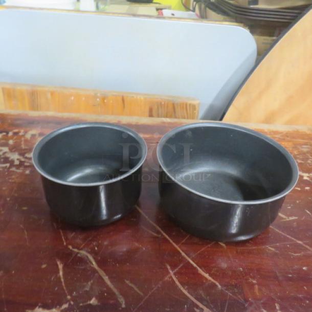 Assorted size Ingenico T-Fal pans, two pieces, black, used condition, non-stick interior, suitable for varying cooking needs.