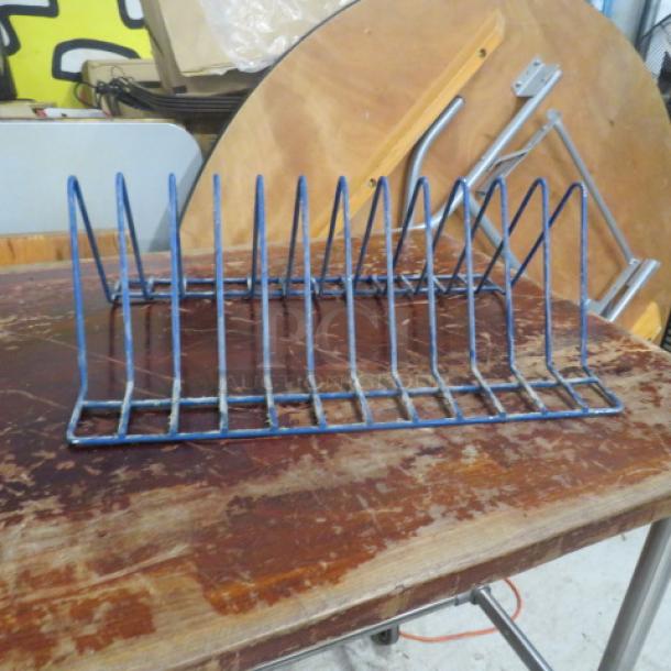 Blue metal one pan rack with multiple vertical slots for organizing. Shows wear and rust on a wooden surface.