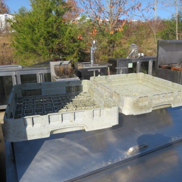 Two used dishwasher racks, light gray, square design, with grid bases. Suitable for commercial use. Outdoor setting background.